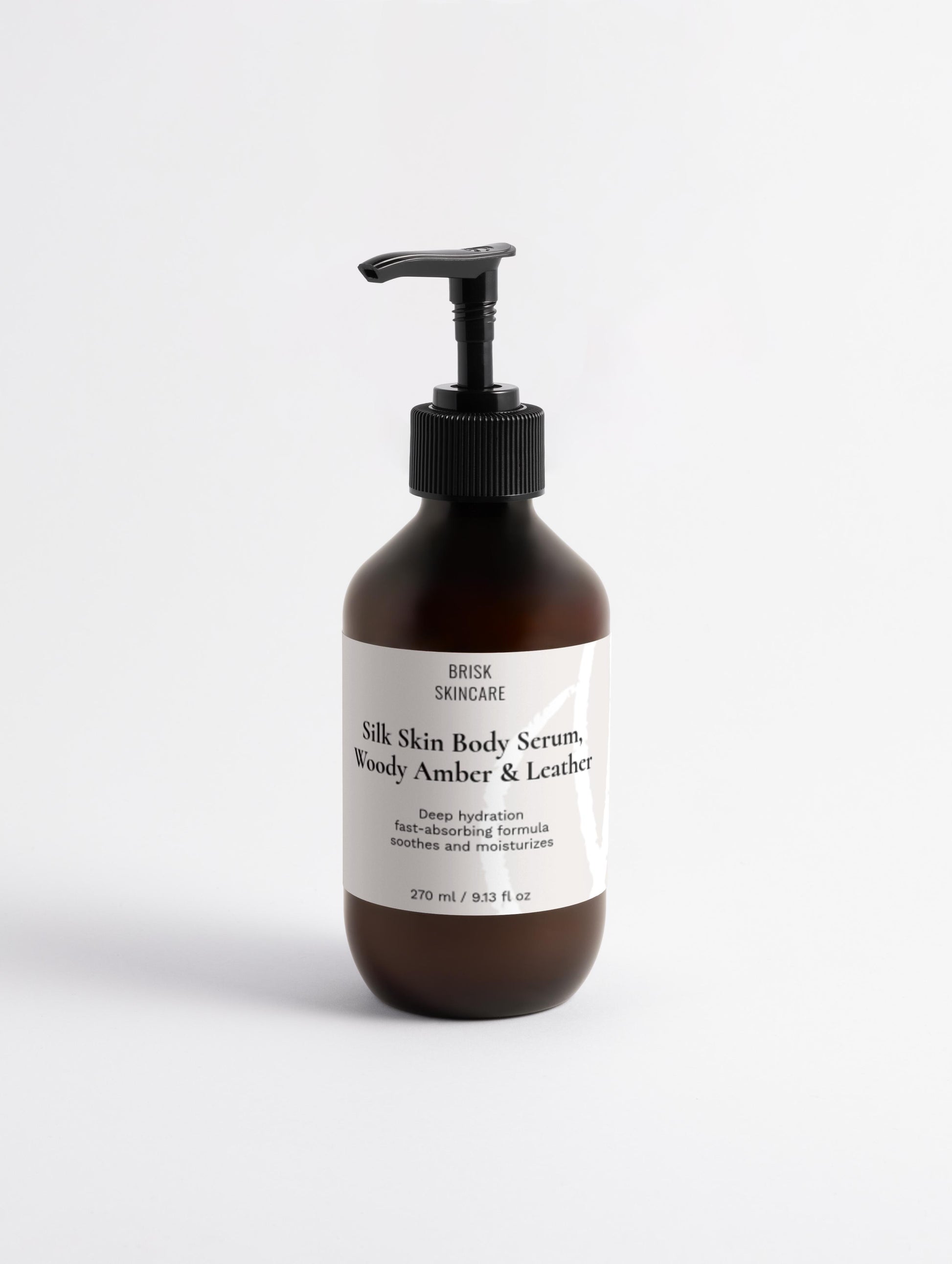 A pump bottle of Silk Skin Body Serum with the text '100% silk skin serum woody amber & leather' on the label.