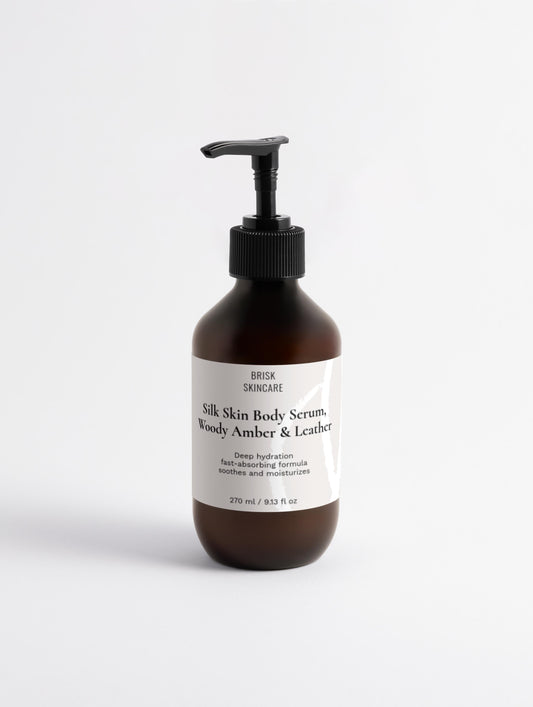 A pump bottle of Silk Skin Body Serum with the text '100% silk skin serum woody amber & leather' on the label.